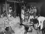 Men cooking a huge pot of Laddu, a common Indian sweet, over an open ...