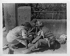 A German nurse assists an 8th Armored Division medic treat a wounded ...