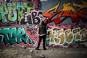 Image of Teenage graffiti artist spray painting a wall - Austockphoto