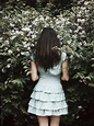 Back view of a young woman standing in front of a bush by Jovana Rikalo ...