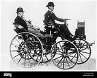 Gottlieb Daimler sits back while his son Adolf takes the wheel of his ...