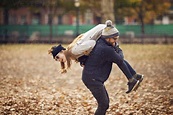 Man carrying woman on shoulder while standing at park stock photo