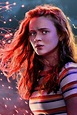 a woman with red hair standing in front of fireworks and looking off to ...