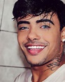 a close up of a person with a smile on their face and tattoos on his chest