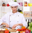 Young woman chef cooking in kitchen — Stock Photo © belchonock #18750673