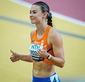 a woman in an orange top running on a track with her hand out to the side