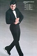 a man in a tuxedo skating on an ice rink with his arms crossed