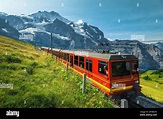 Bergbahn mit moderner Zahnrad roter Touristenbahn auf der Piste. Eine ...