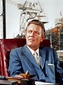 a man sitting in a chair wearing a suit and tie