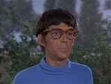 a man wearing glasses and a blue sweater
