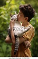 teenager boy with cat kiss hug on green summer grass close up photo