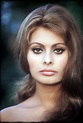 a woman with long hair and brown eyes looks at the camera while posing ...