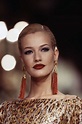 a woman with red lipstick and earrings on the runway at a fashion show ...