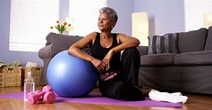 Senior Black woman sitting on floor with exercise equipment | X10 Therapy