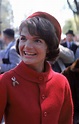 a woman in a red coat and hat smiles at the camera with other people ...