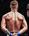 a man with tattoos on his back holding a blue boxing glove