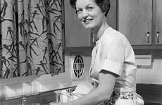 1960s housewife woman dishes washing vintage kitchen sink camera looking photograph
