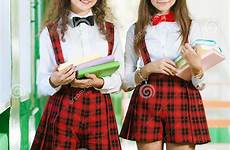 schoolgirls stanno scolare uniformi stando libri divertenti corridoio