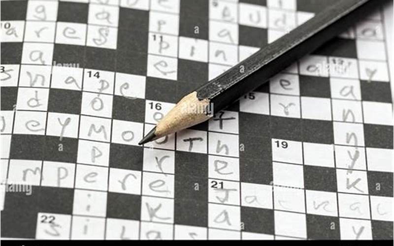 Person Using A Pencil On A Crossword Puzzle