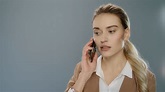 Serious business woman talking mobile phone on gray background ...