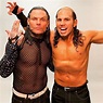 two men in fishnet tops posing for the camera with one holding his hands up