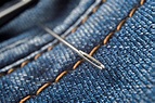 Premium Photo | Sewing needle lies on the seam of blue denim