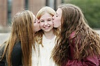 Close up of smiling sisters kissing outdoors - Stock Photo - Dissolve