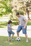 Padre e hijo jugando al fútbol en el parque | Foto Premium