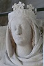 a white statue with a crown on it's head and scarf around its neck