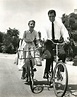 John Gavin and Cicely Evans ride bikes.