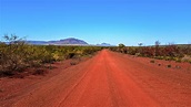 Outback red dirt road leading to mountain and blue sky Photograph by ...