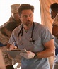 a man in scrubs is holding a clipboard and looking at the camera while ...