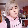 a man with grey hair wearing a pink hoodie and black backpack in a kitchen