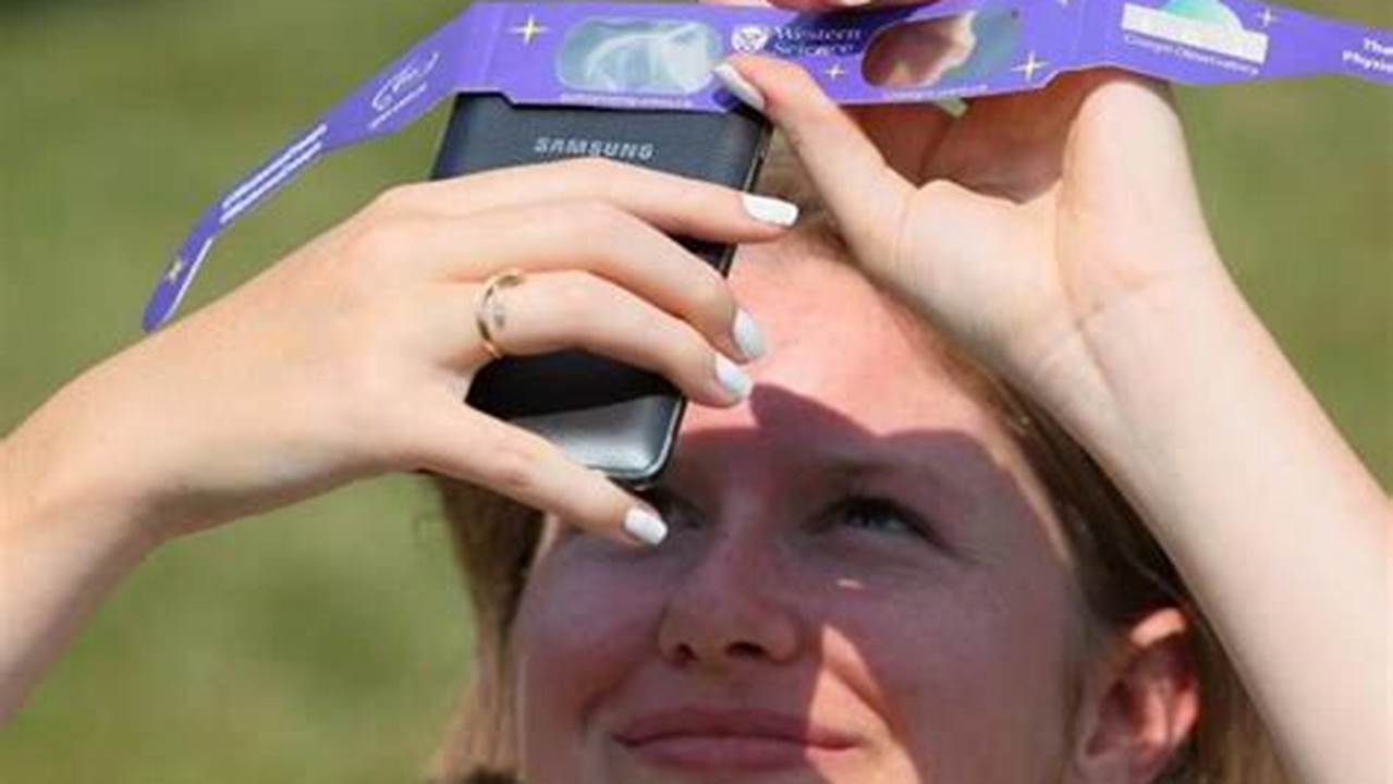 Mélanie Meinrad Holds Solar Glasses Over Her Phone To Take A Photo Of The Partial Solar Eclipse On Aug., 2024