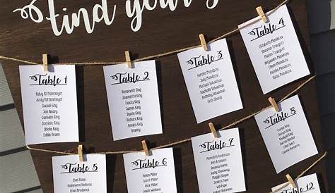 a seating chart is hanging on a wooden board with clothes pins attached
