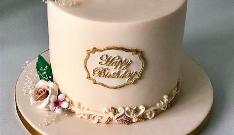a white cake with pink flowers and gold leaves