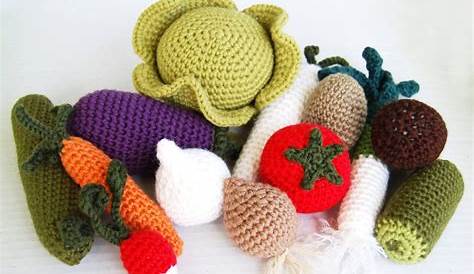 several knitted fruits and vegetables laid out on a wooden surface with