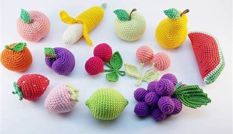 several knitted fruits and vegetables laid out on a wooden surface with