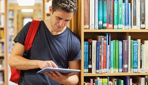 Retrato de joven estudiante leyendo un libro en una biblioteca | Foto