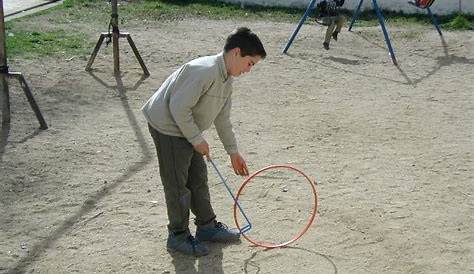 Niño jugando con aro de juguete con las manos y el aro está rodando en