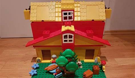 a lego house is shown with flowers and plants in the front yard, on a