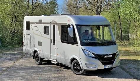 an rv is parked in the grass next to some picnic tables and chairs with