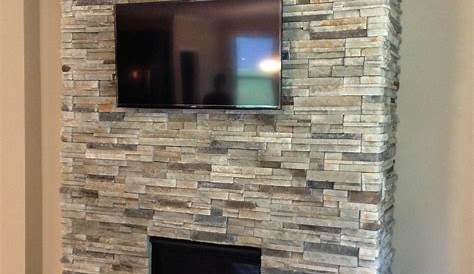 Black stacked stone fireplace with reclaimed natural wood mantel in