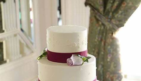 Clean and modern wedding cake with wine-colored ribbon and fresh flower