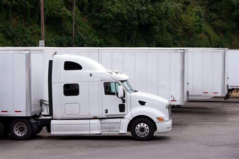 White Semi Truck With Trailer Whating Cargo On Parking Lot In Row With