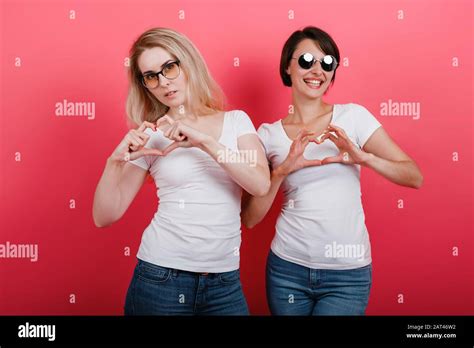 Two Women In Glasses Looking Happy Showing A Heart Gesture From Fingers