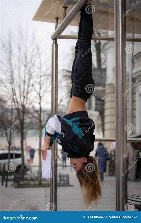 Girl Hanging By Feet Upside Down In The Street And Reading Book Concept Of Education And Self
