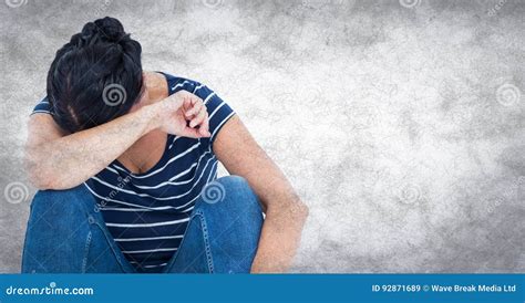 Woman Sitting And Crying Into Arm Against White Wall With Grunge