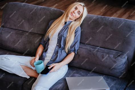 premium photo tired blonde beautiful woman sitting on sofa at home holding phone swedish