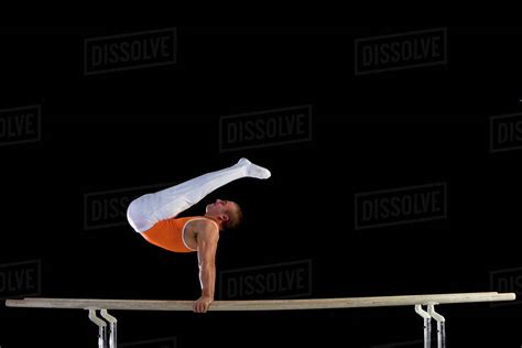 Male Gymnast Performing On Parallel Bars Side View Stock Photo